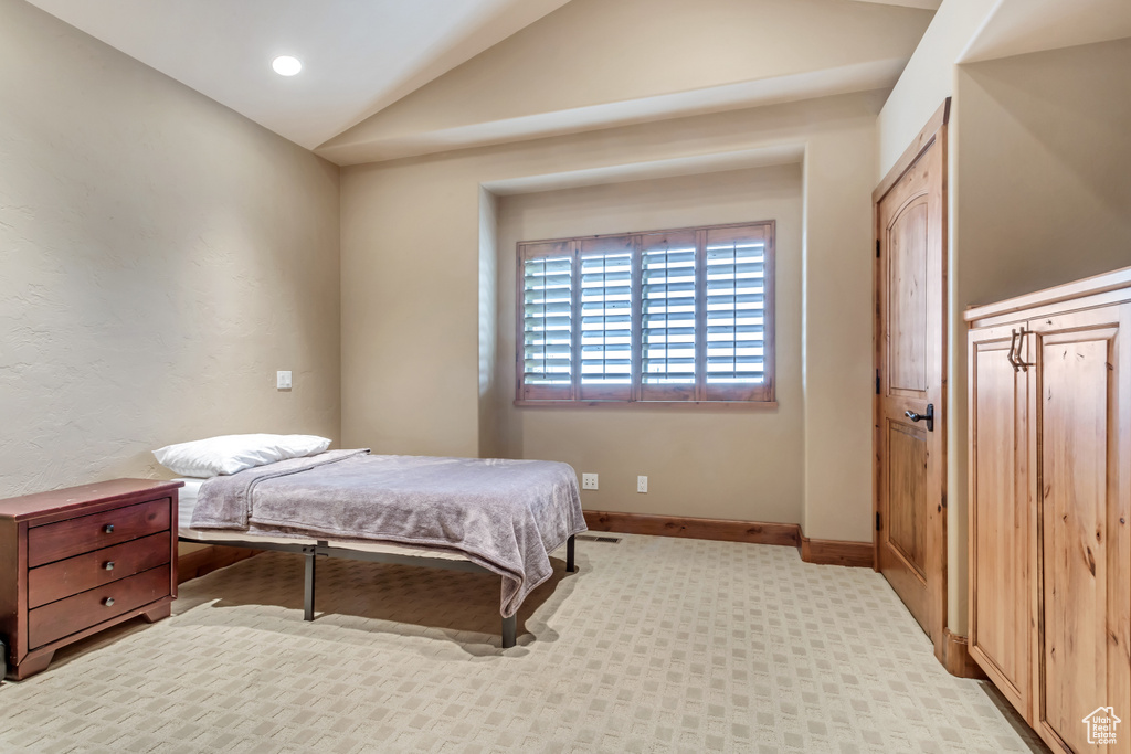 Bedroom with light carpet and lofted ceiling