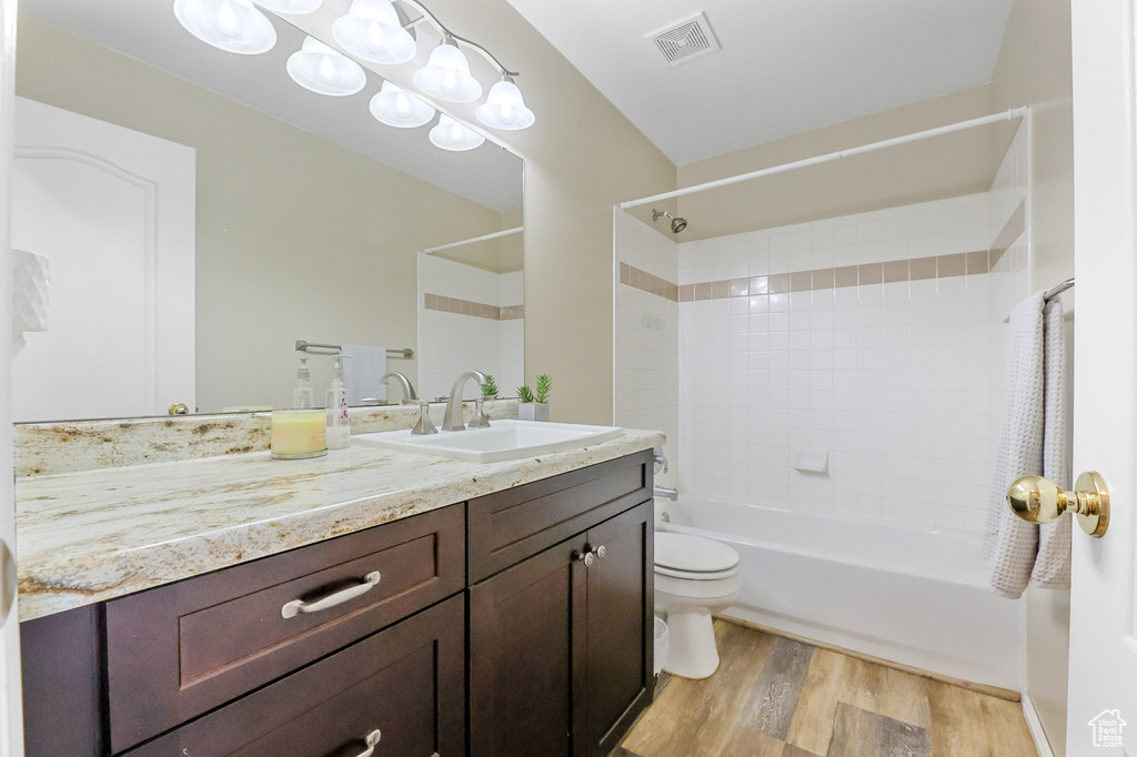 Full bathroom featuring tiled shower / bath, vanity, wood-type flooring, and toilet