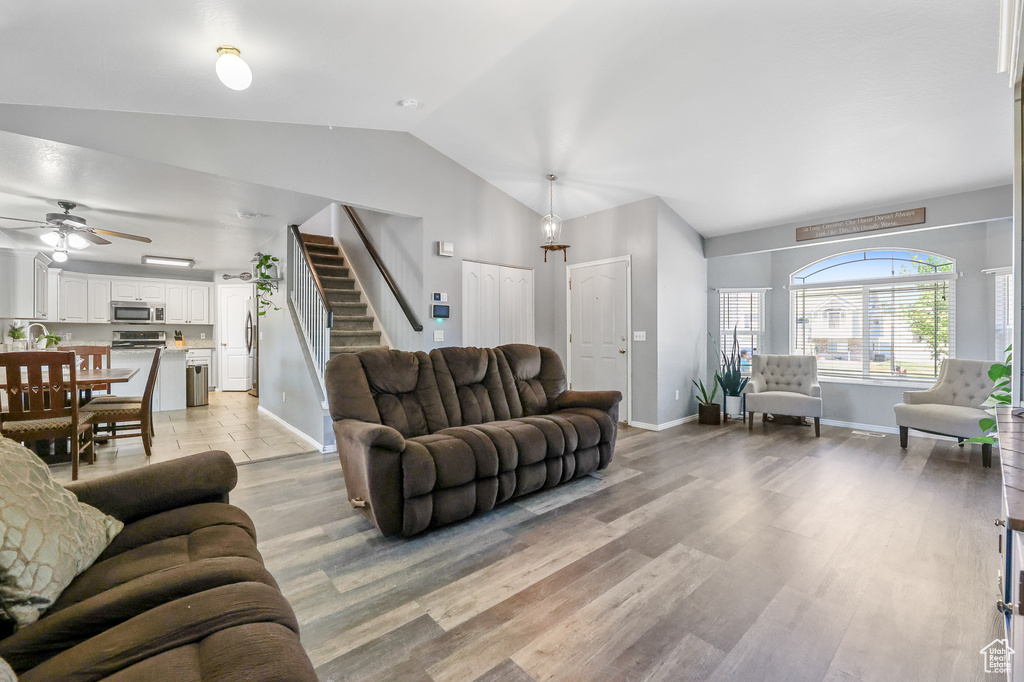 Living room with ceiling fan, sink, light hardwood / wood-style flooring, and vaulted ceiling