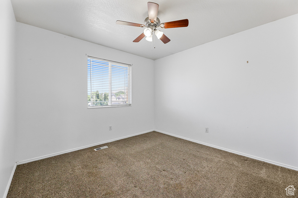 Carpeted spare room with ceiling fan