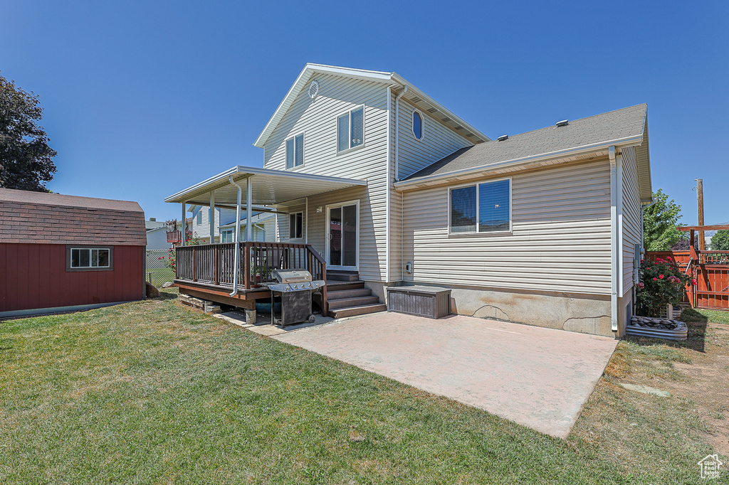 Rear view of property with an outdoor structure, a patio area, and a yard