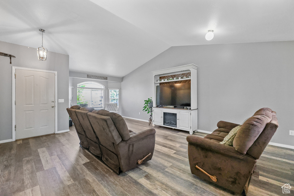 Living room with wood-type flooring, vaulted ceiling, and a chandelier