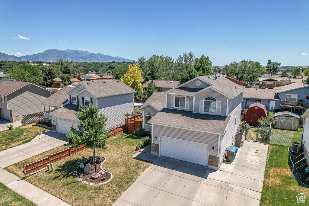 View of front of property featuring a storage unit, a garage, central AC unit, a mountain view, and a front yard