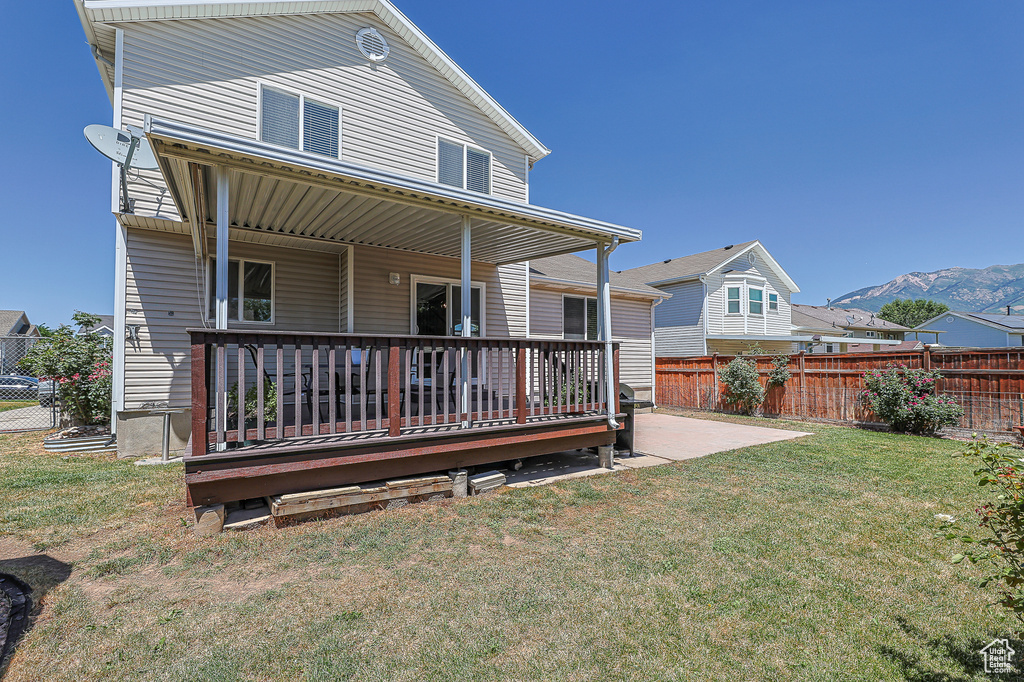 Rear view of property featuring a mountain view and a lawn