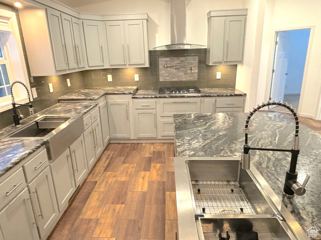 Kitchen featuring sink, tasteful backsplash, hardwood / wood-style flooring, and wall chimney range hood