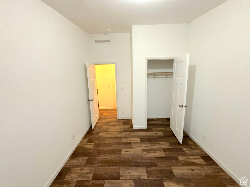 Unfurnished bedroom featuring dark hardwood / wood-style flooring and a closet