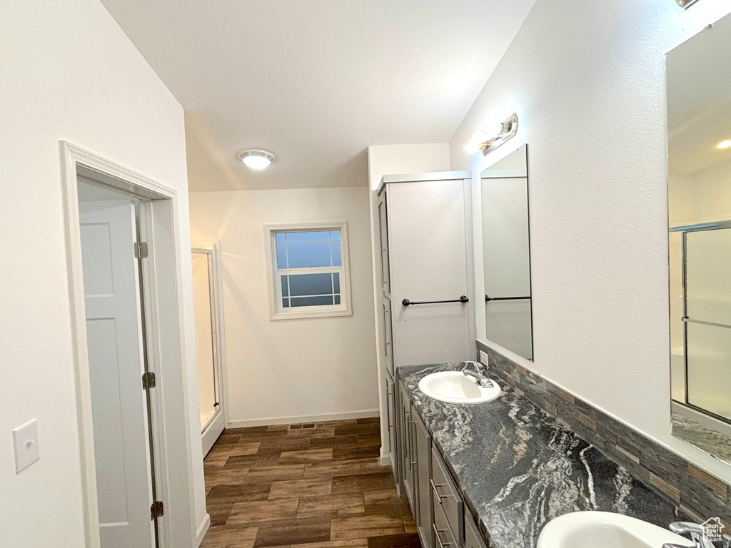 Bathroom with double vanity, walk in shower, and hardwood / wood-style flooring