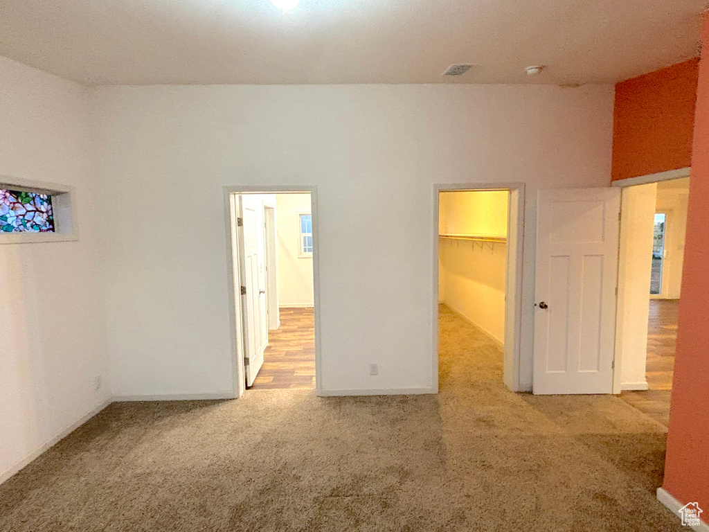 Unfurnished bedroom with a closet, carpet flooring, and a walk in closet