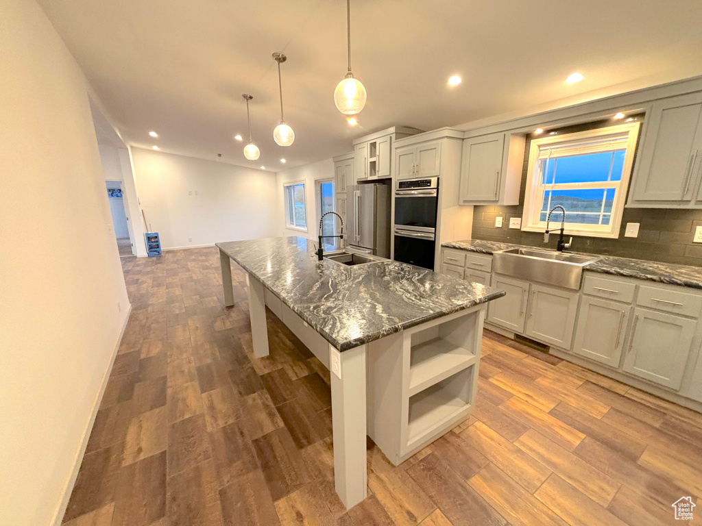 Kitchen featuring hardwood / wood-style floors, sink, a center island with sink, and a kitchen bar