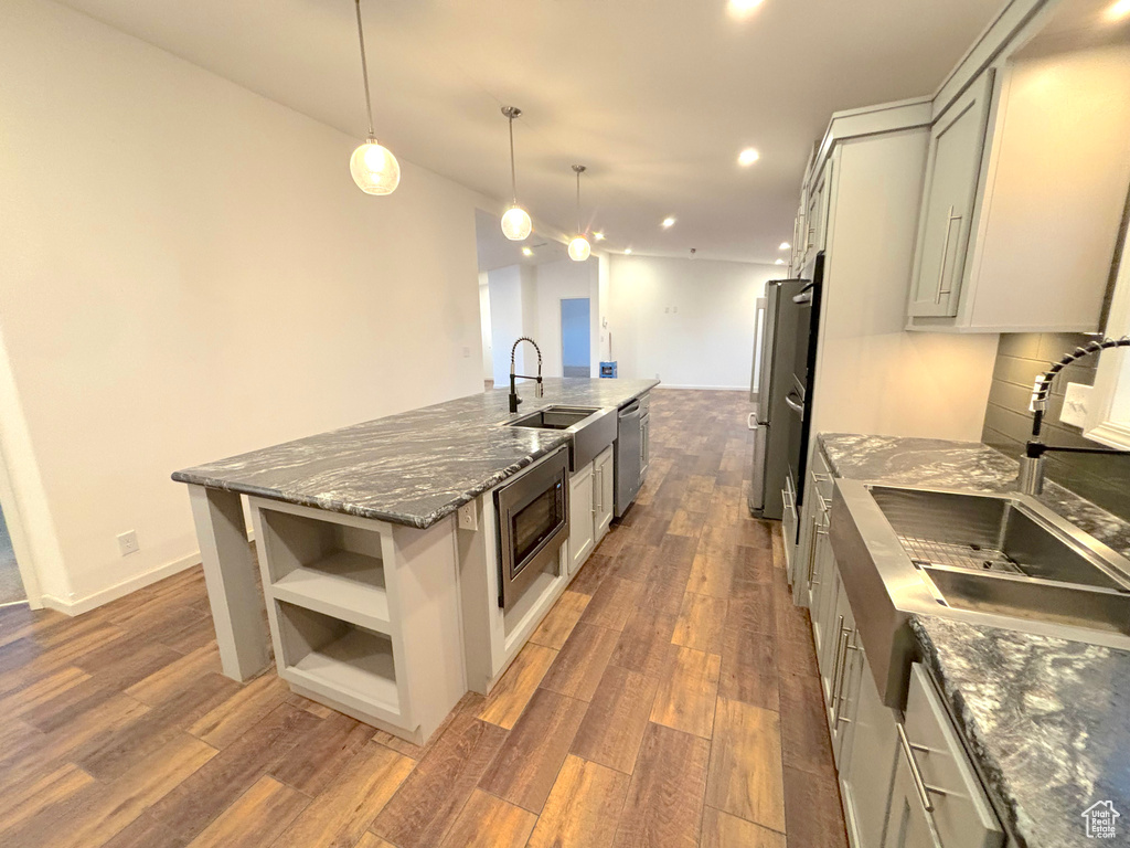 Kitchen featuring appliances with stainless steel finishes, sink, hardwood / wood-style floors, and an island with sink