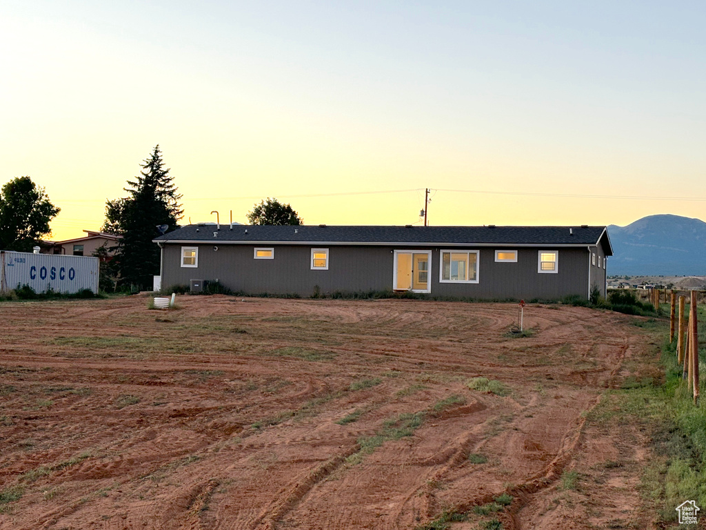 Back house at dusk with a mountain view and cooling unit