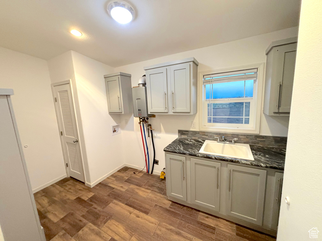 Kitchen with dark stone countertops, sink, and hardwood / wood-style flooring
