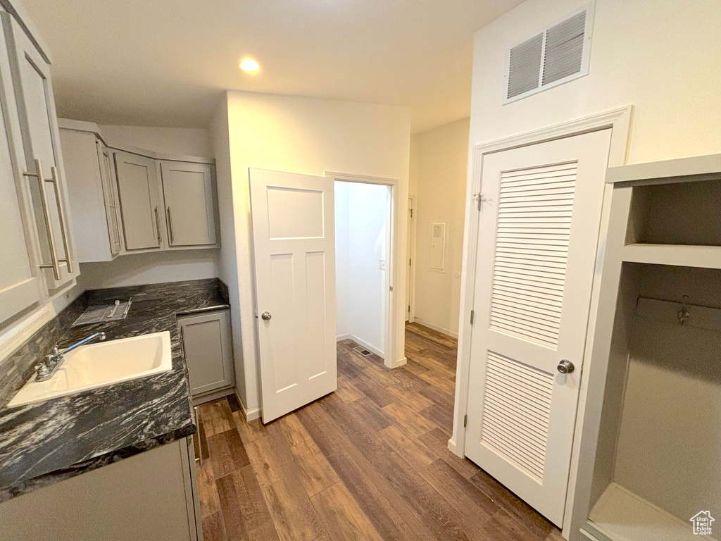 Kitchen featuring sink, dark hardwood / wood-style floors, and dark stone counters