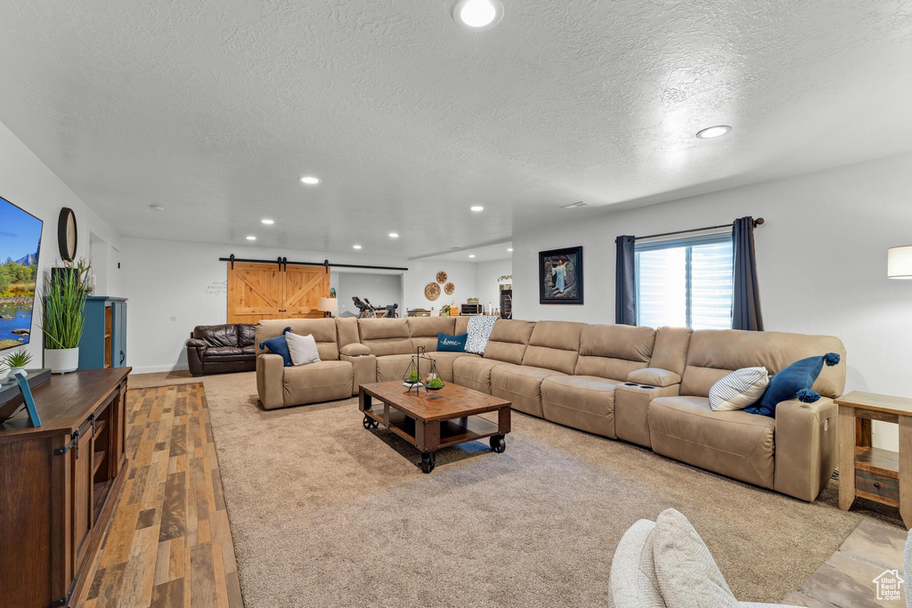 Living room with light hardwood / wood-style flooring, a barn door, and a textured ceiling