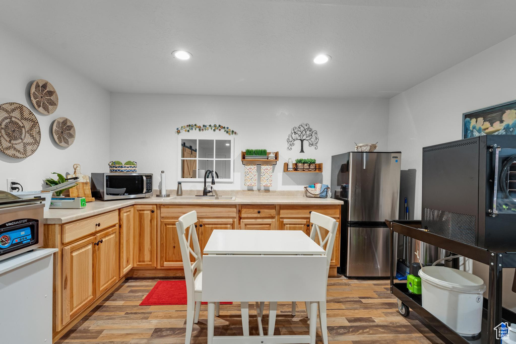 Kitchen featuring appliances with stainless steel finishes, light wood-type flooring, light brown cabinetry, and sink