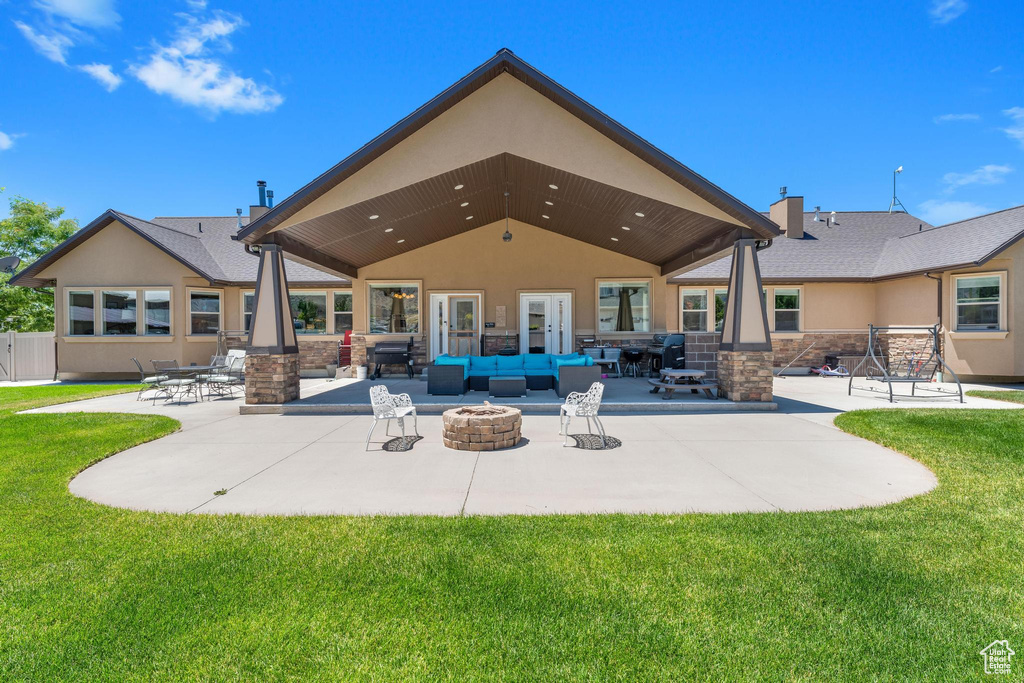 Back of property with an outdoor living space with a fire pit, a patio, and a lawn