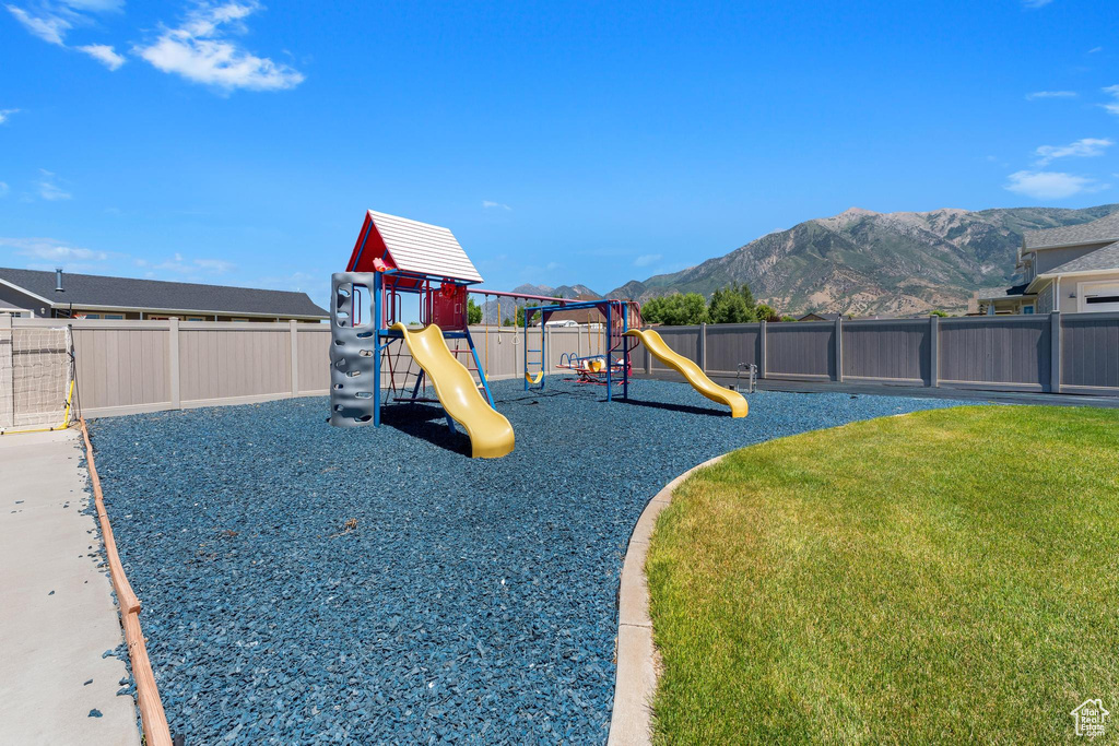 View of jungle gym featuring a lawn and a mountain view