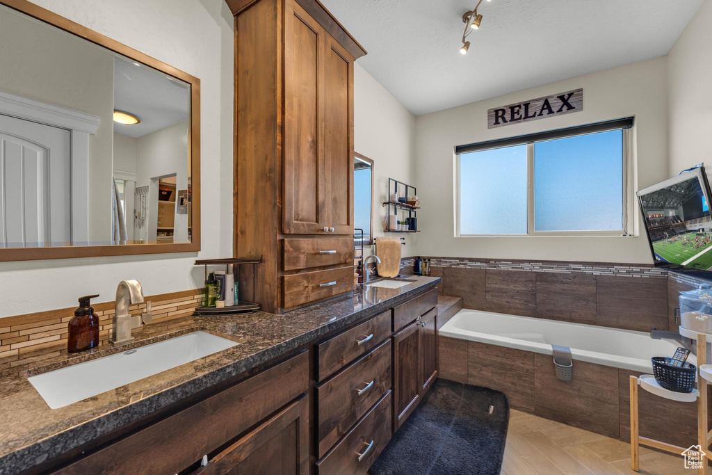 Bathroom with tiled bath and double sink vanity