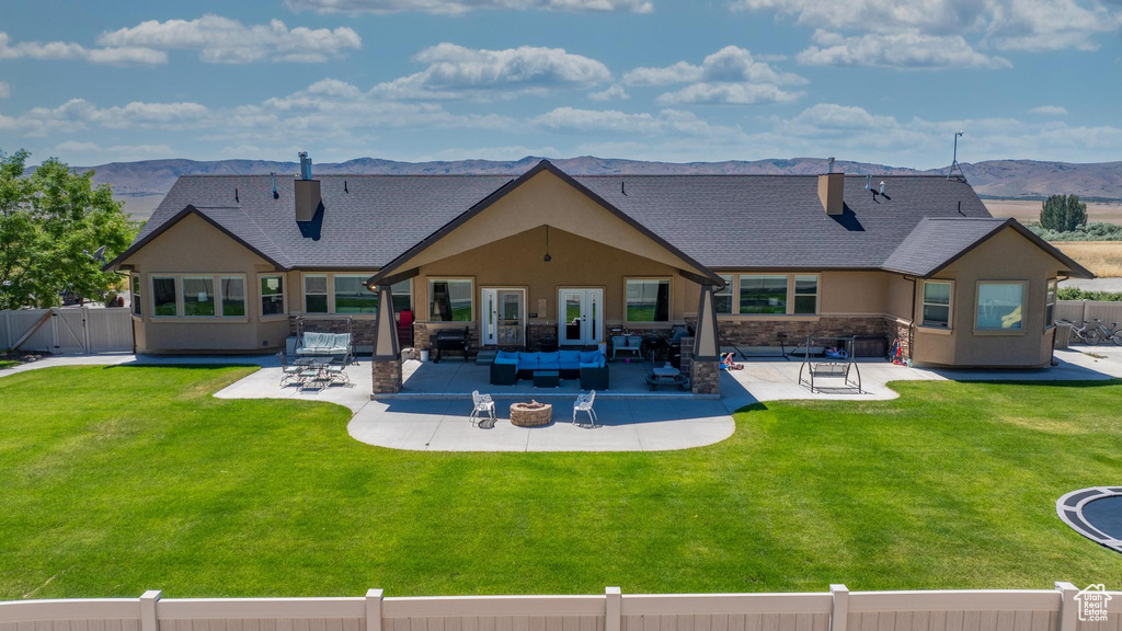 Back of property with a mountain view, a patio area, and a yard