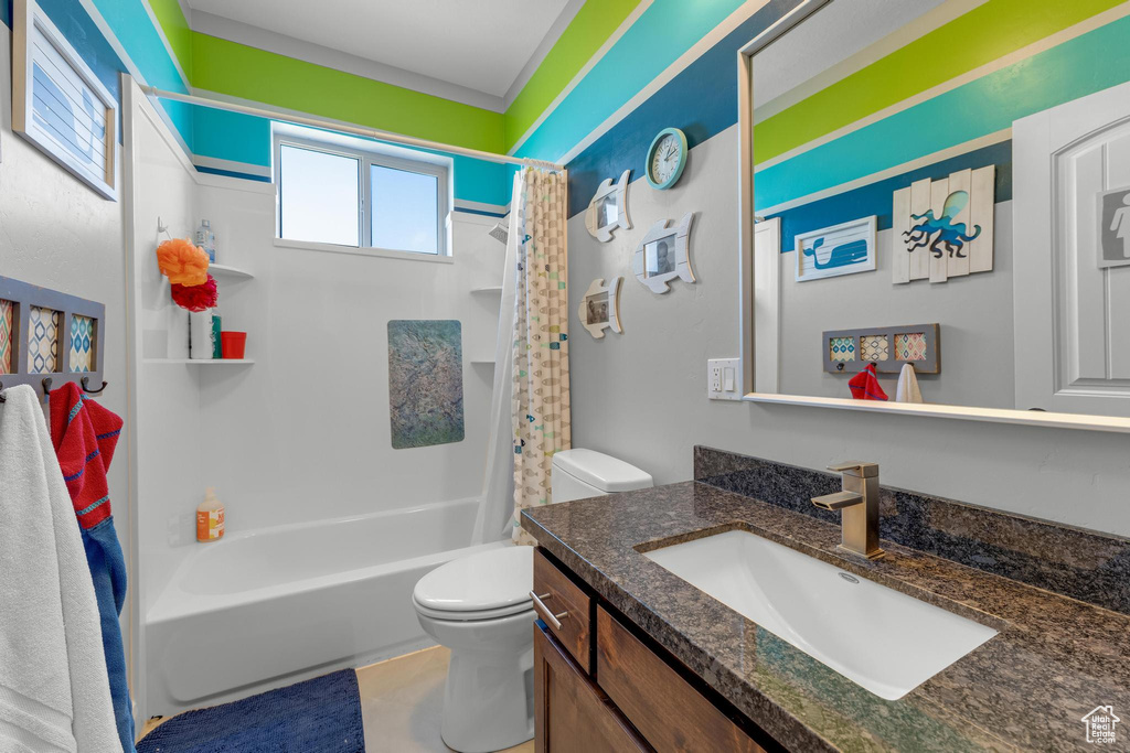 Full bathroom with shower / bath combo with shower curtain, vanity, and toilet