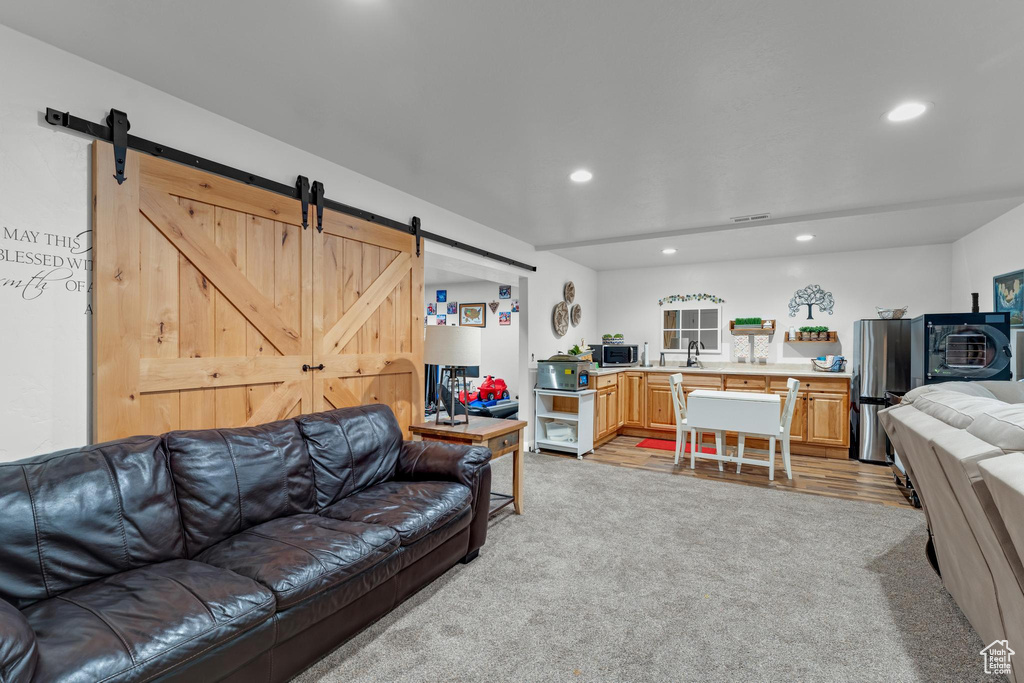 Living room with sink, light hardwood / wood-style flooring, and a barn door