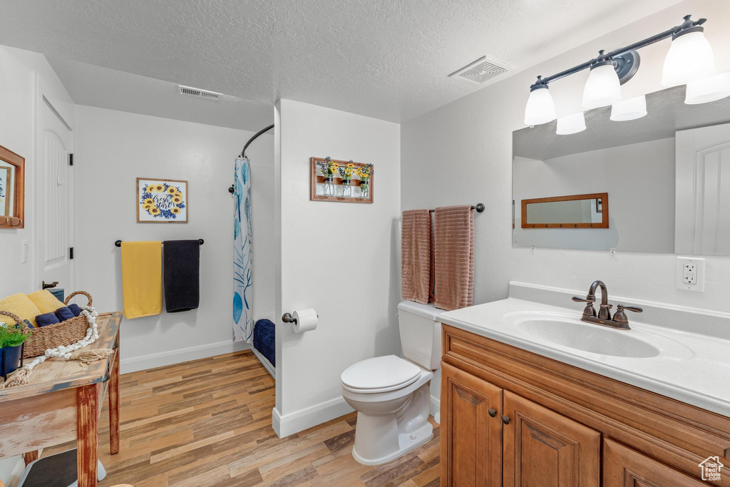 Bathroom with vanity, a textured ceiling, hardwood / wood-style flooring, and toilet