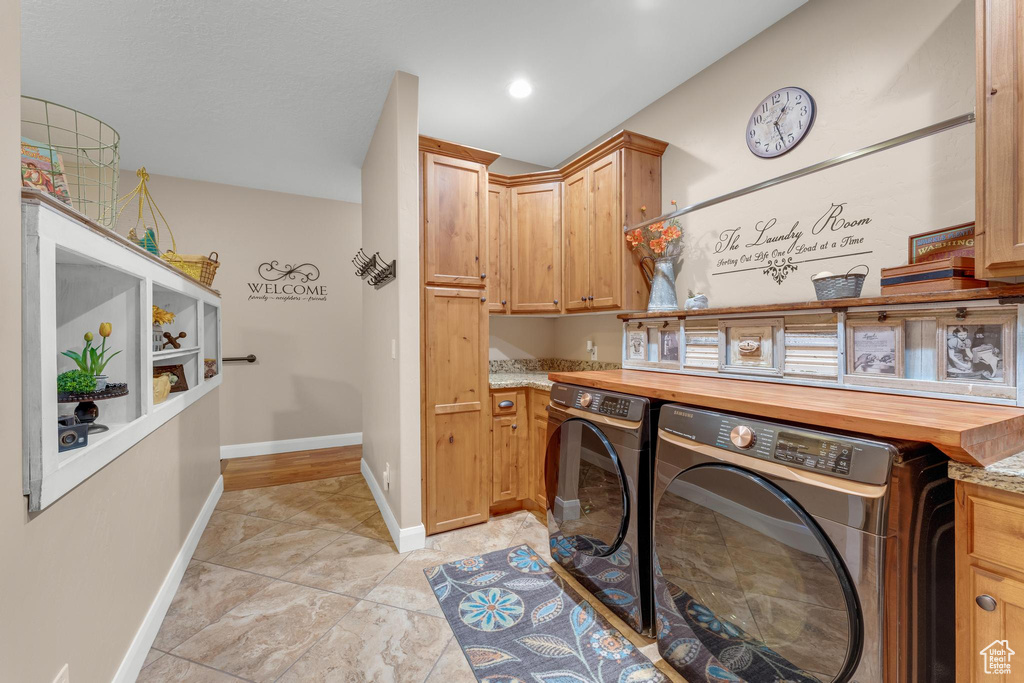 Laundry area featuring light tile patterned flooring, cabinets, and washer and dryer