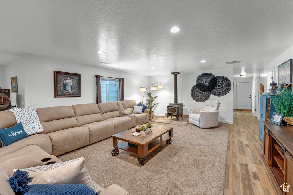 Living room with a wood stove, a textured ceiling, and hardwood / wood-style floors