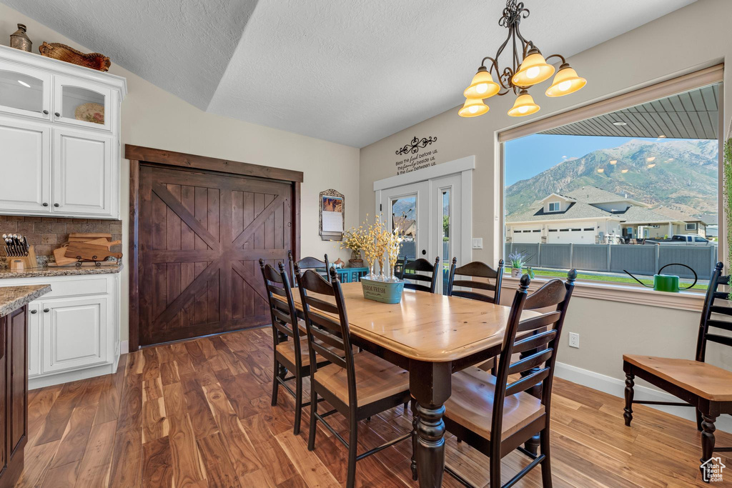 Dining room featuring a notable chandelier, a textured ceiling, a mountain view, dark hardwood / wood-style floors, and vaulted ceiling