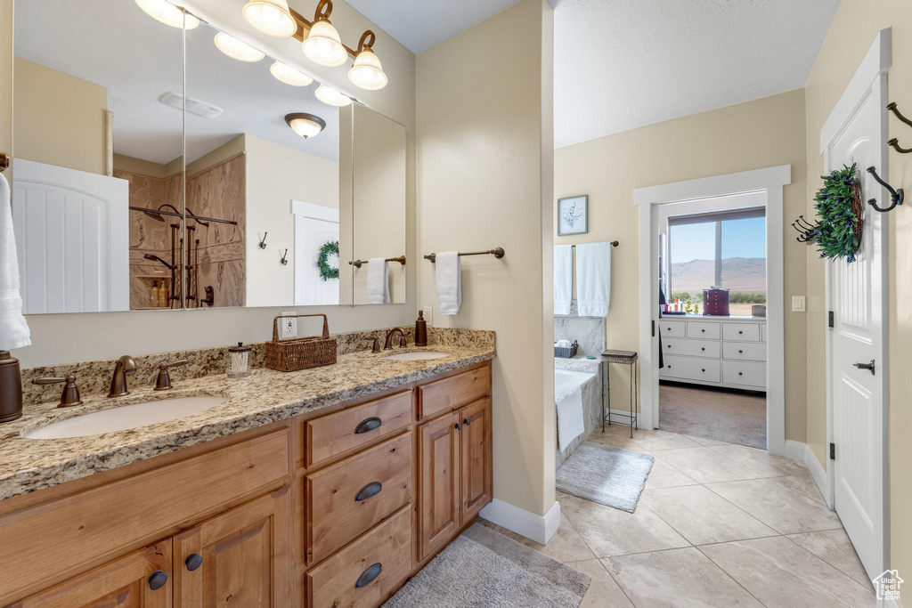 Bathroom featuring double vanity, shower with separate bathtub, and tile patterned floors