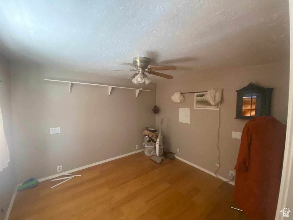 Laundry room with a wall mounted air conditioner, ceiling fan, and hardwood / wood-style flooring