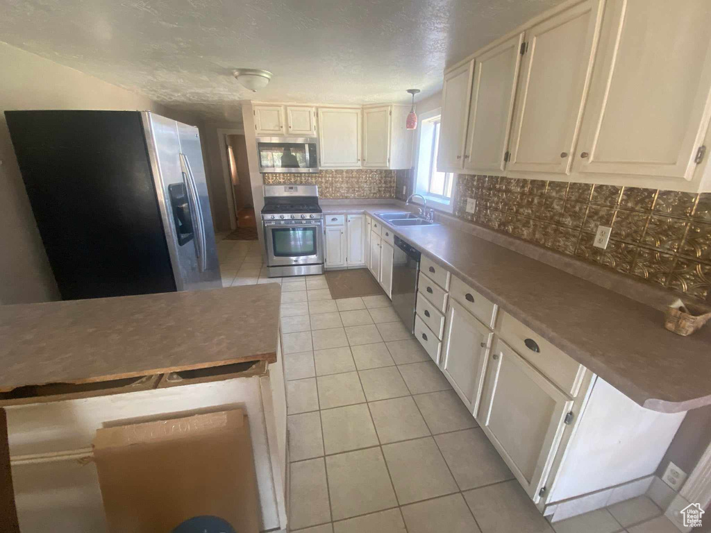 Kitchen featuring white cabinetry, stainless steel appliances, backsplash, and light tile patterned floors