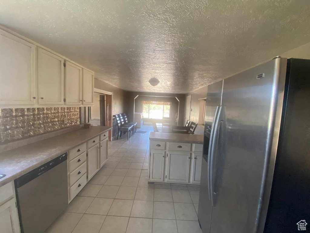 Kitchen featuring appliances with stainless steel finishes, a textured ceiling, white cabinets, and light tile patterned floors