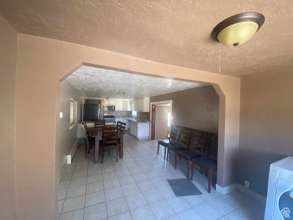 Dining area with light tile patterned flooring, washer / dryer, and a textured ceiling