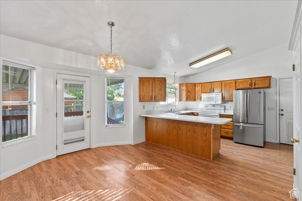 Kitchen with lofted ceiling, light hardwood / wood-style flooring, kitchen peninsula, and white appliances