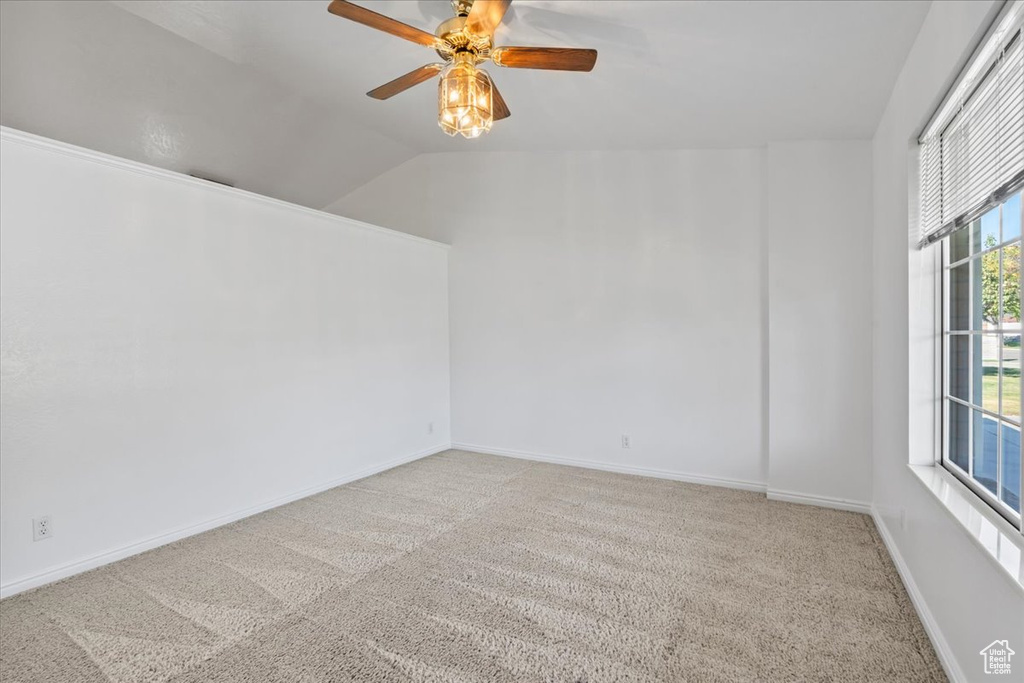 Spare room with ceiling fan, carpet flooring, and lofted ceiling