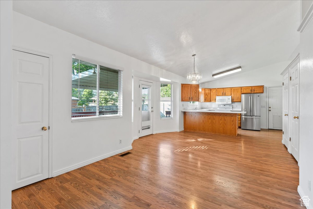 Kitchen featuring light hardwood / wood-style flooring, stainless steel refrigerator, lofted ceiling, and pendant lighting