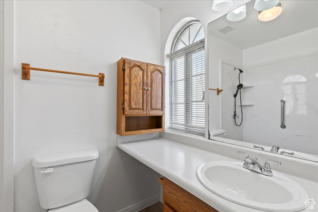 Bathroom with vanity, toilet, and a shower