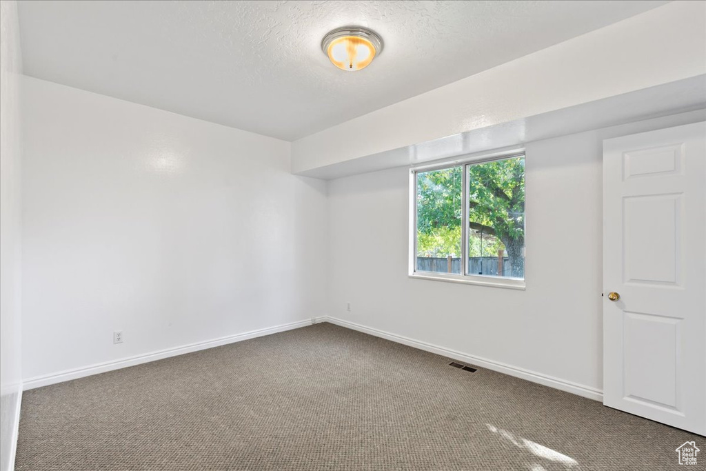 Carpeted empty room with a textured ceiling