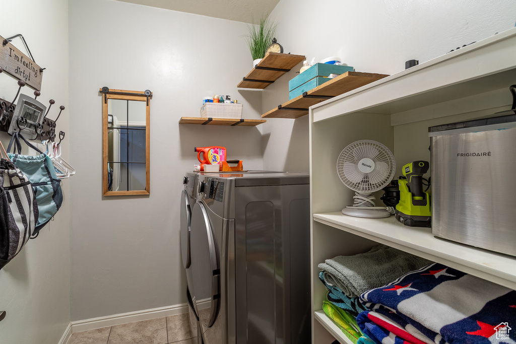 Washroom with washing machine and dryer and light tile patterned floors