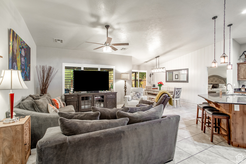 Living room with a healthy amount of sunlight, light tile patterned flooring, ceiling fan, and vaulted ceiling