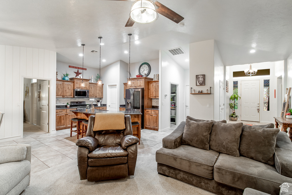 Living room with light tile patterned flooring, sink, and ceiling fan with notable chandelier