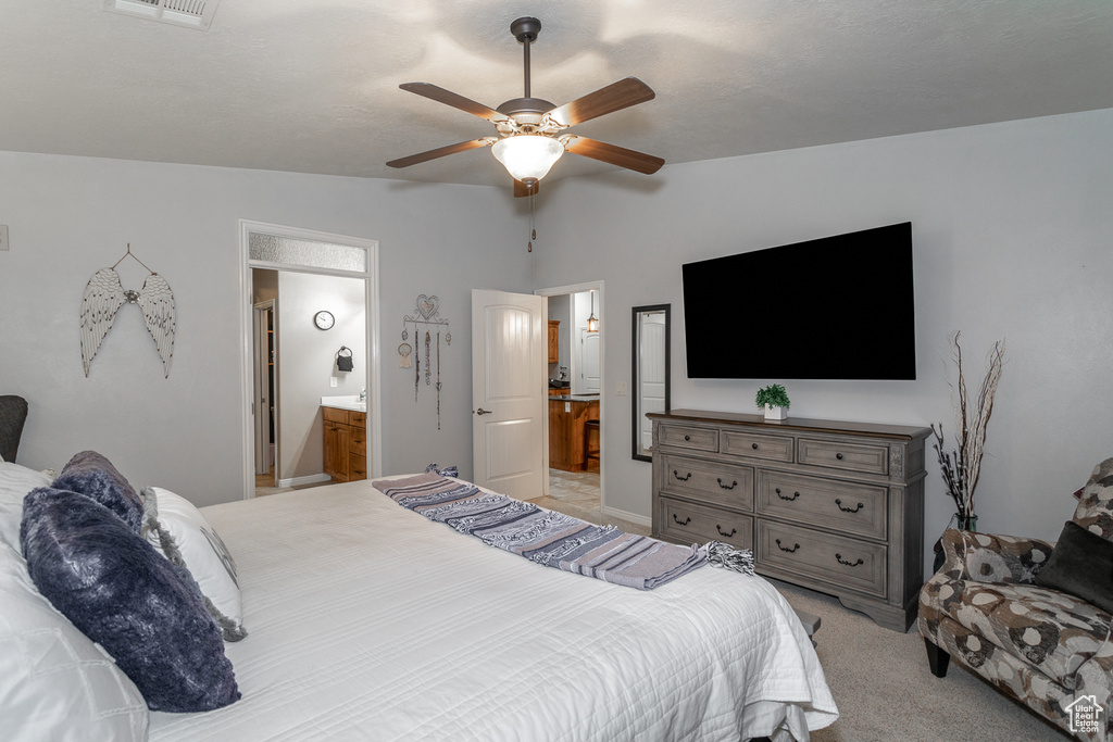 Bedroom featuring lofted ceiling, light carpet, ensuite bath, and ceiling fan