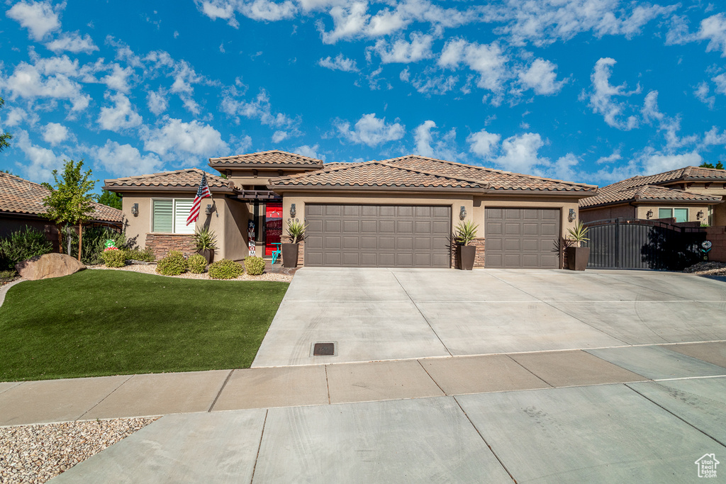 View of front of property featuring a garage and a front lawn