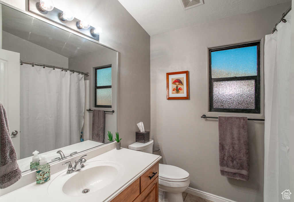 Bathroom featuring vanity, toilet, and tile patterned flooring