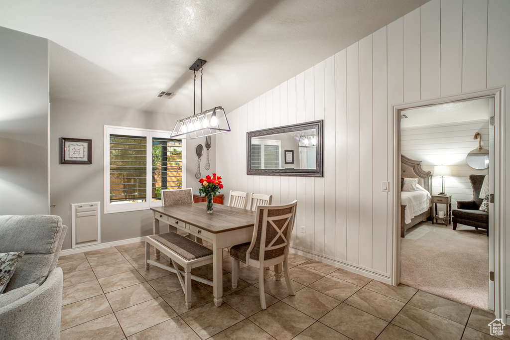 Carpeted dining space featuring lofted ceiling and a notable chandelier