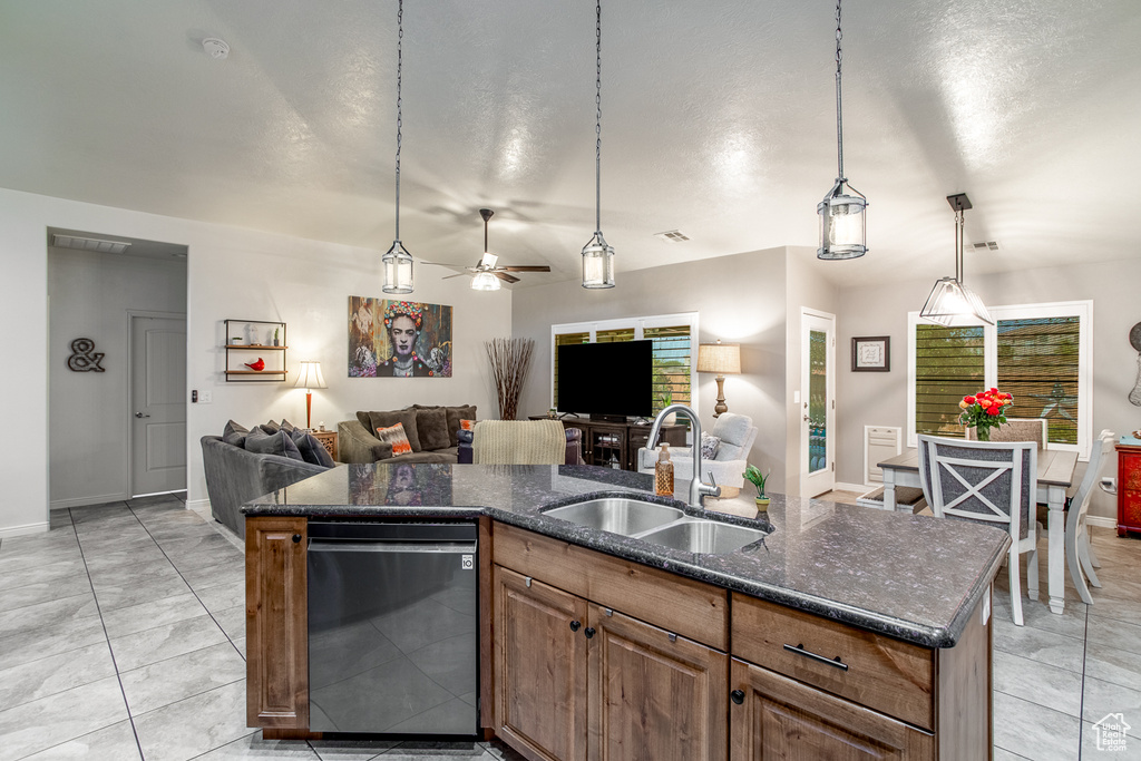 Kitchen featuring black dishwasher, a center island with sink, sink, light tile patterned floors, and ceiling fan