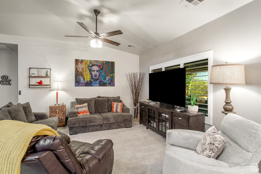 Living room with lofted ceiling, light colored carpet, and ceiling fan