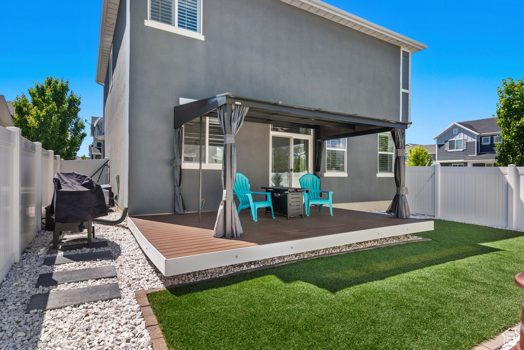 Rear view of house with a deck and a lawn