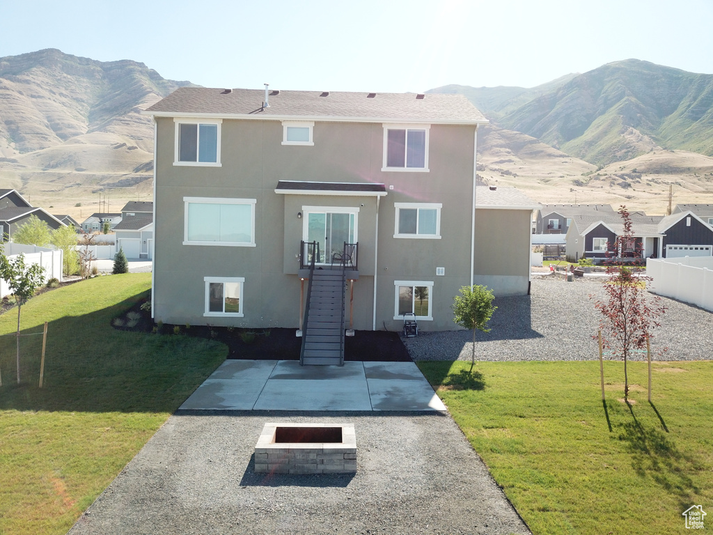 View of front of home with a mountain view, a patio, and a front lawn